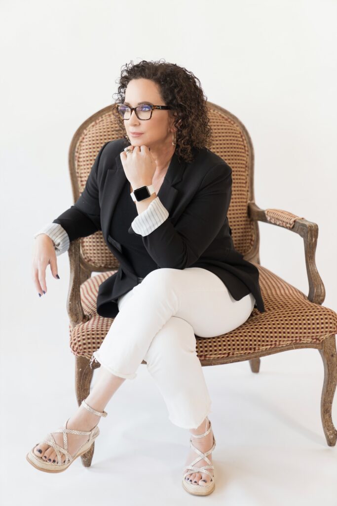 Simone Knego, keynote speaker, seated in an armchair